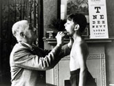 image: A doctor checks a young boy's tonsils, December 1935